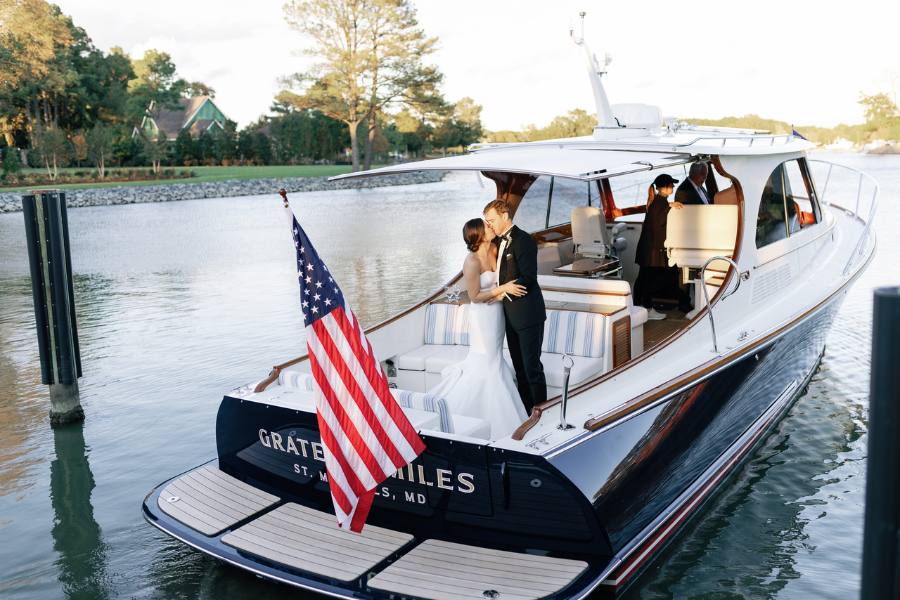 Married couple on the back of a yacht sailing into the ocean.
