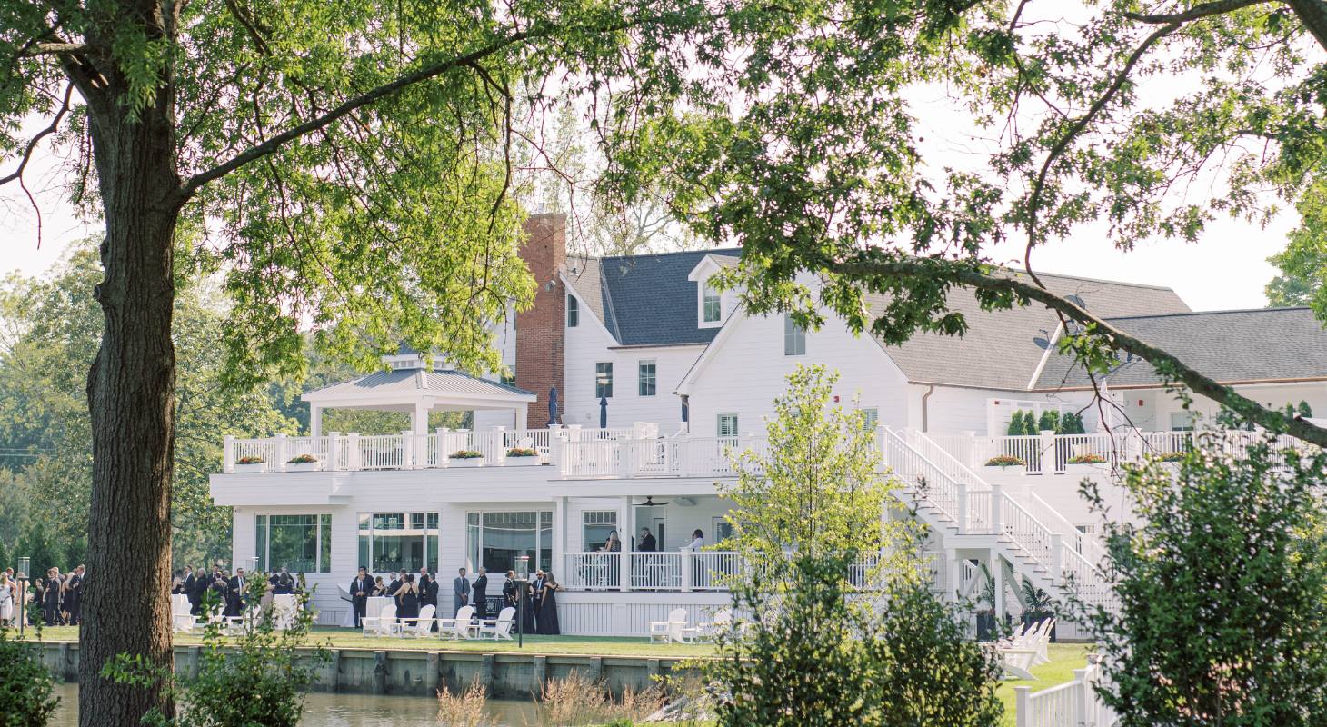 Far-away view of The Oaks Waterfront Hotel with a wedding reception occurring on the lawn